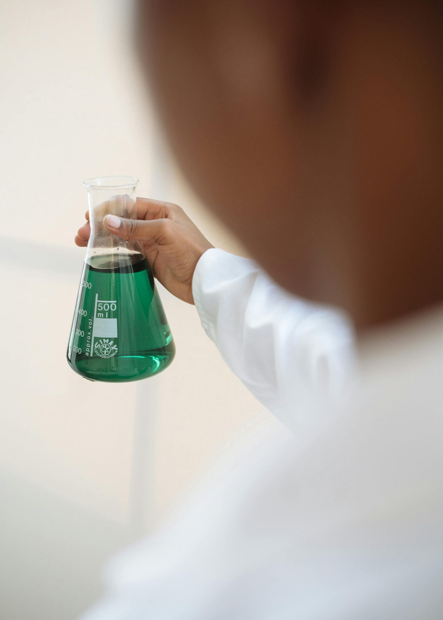 A scientist in a lab coat holding a flask with green liquid, focusing on scientific research.